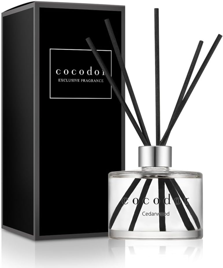 Cocod'or cedar wood reed diffuser in a clear glass bottle with black reeds beside its black box.