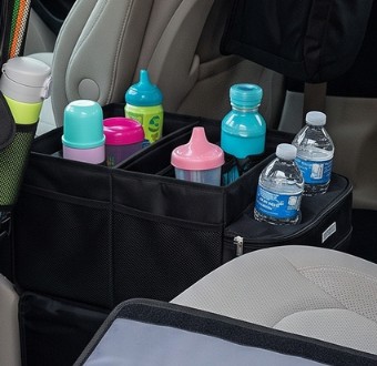 Black car seat organizer sitting between the front seats, holding water bottles, sippy cups, and a coffee tumbler.