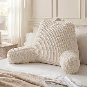 Off-white ribbed reading pillow with arms and a top handle on a bed.