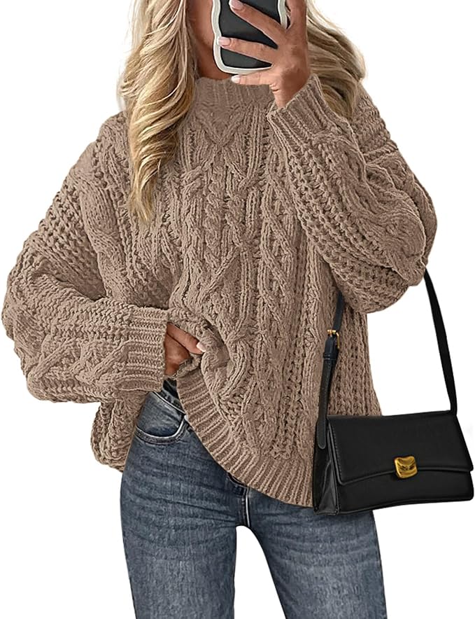 Woman wearing an oversized camel cable knit sweater with jeans and a black shoulder bag.