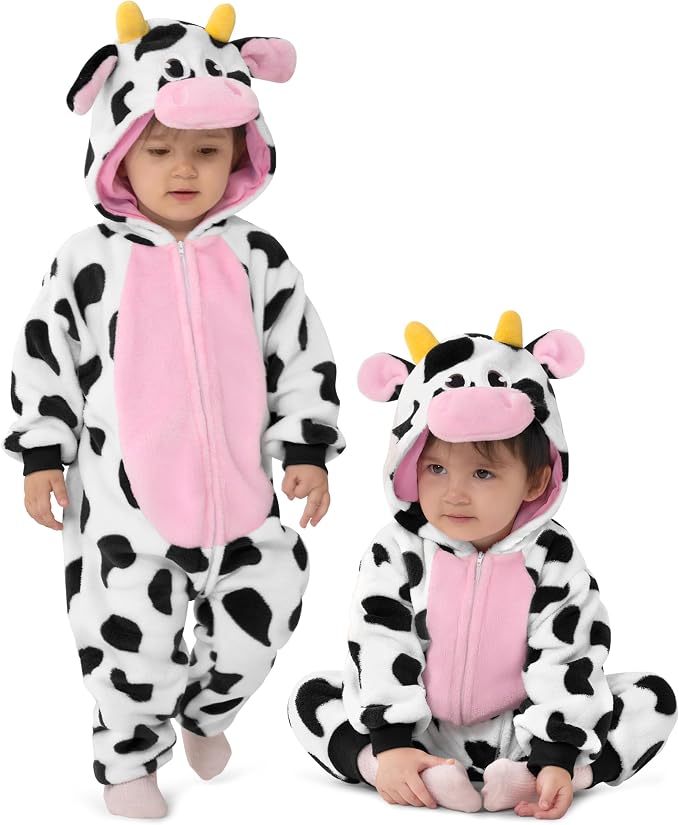 Toddlers wearing white fleece cow onesies with black spots, a pink belly, and a hood with ears and horns.