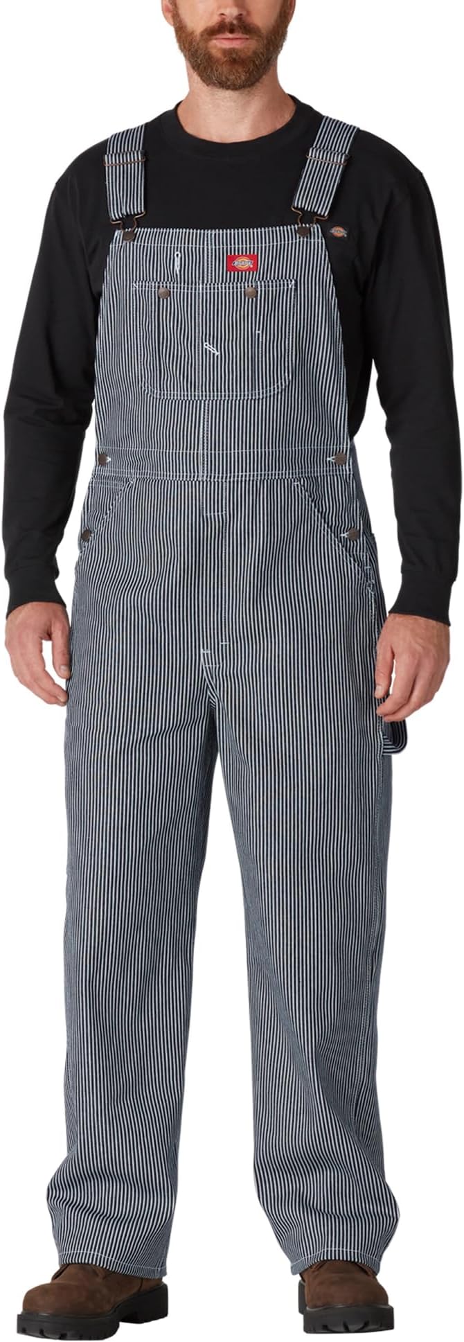 Man wearing black-and-white striped denim bib overalls over a black long-sleeve shirt.