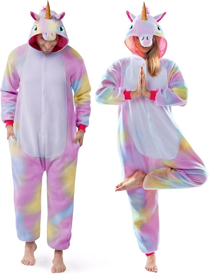 Two adults wearing pastel rainbow unicorn onesie jumpsuits with hoods that have a gold horn and unicorn face.