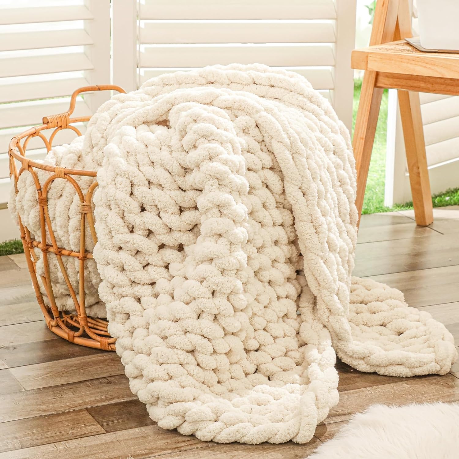 Cream chunky knit throw blanket draped over a woven rattan basket.