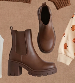 Pair of brown leather chelsea ankle boots with lug soles on a warm tan background.