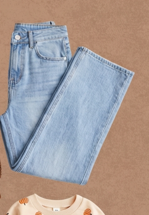 Light wash high waisted wide leg jeans folded on a warm tan background.